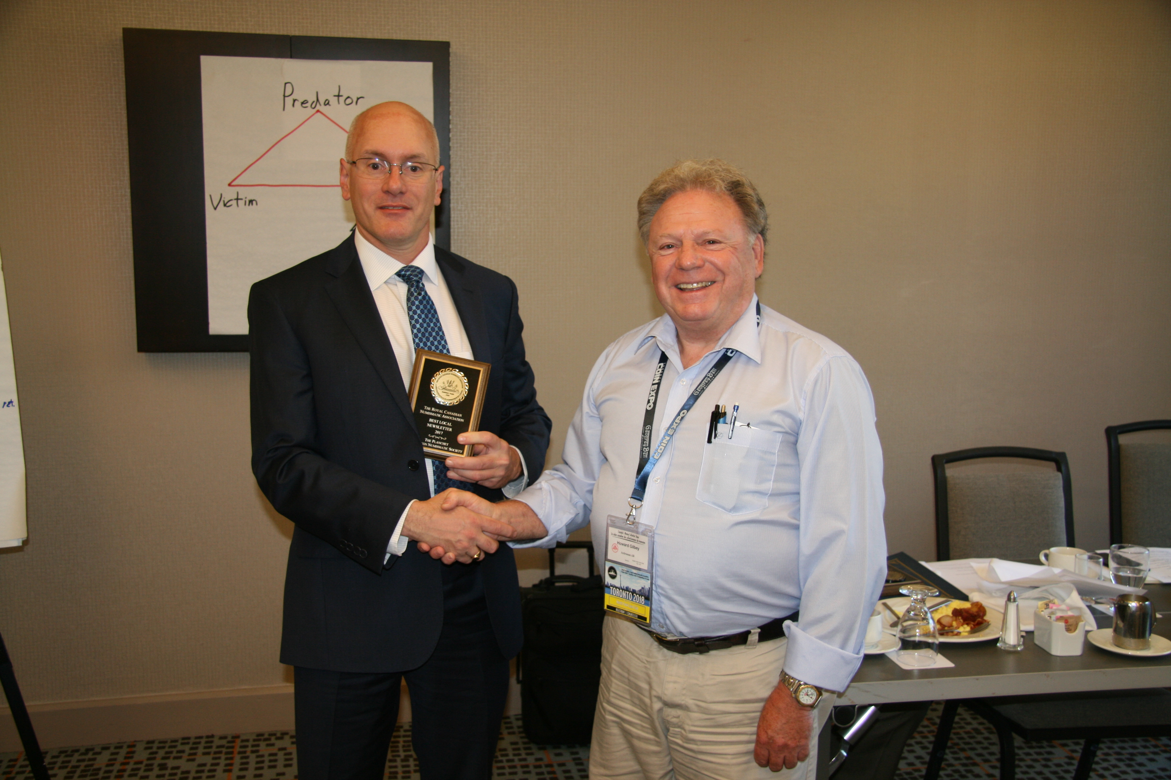 <p><strong>Edmonton Numismatic Society</strong> received the Best Local Club Newsletter Award. Howard Gilbey (right) accepting the award from <strong>Brett Irick</strong> (left).<br> <small>Dan Gosling photo</small></p>