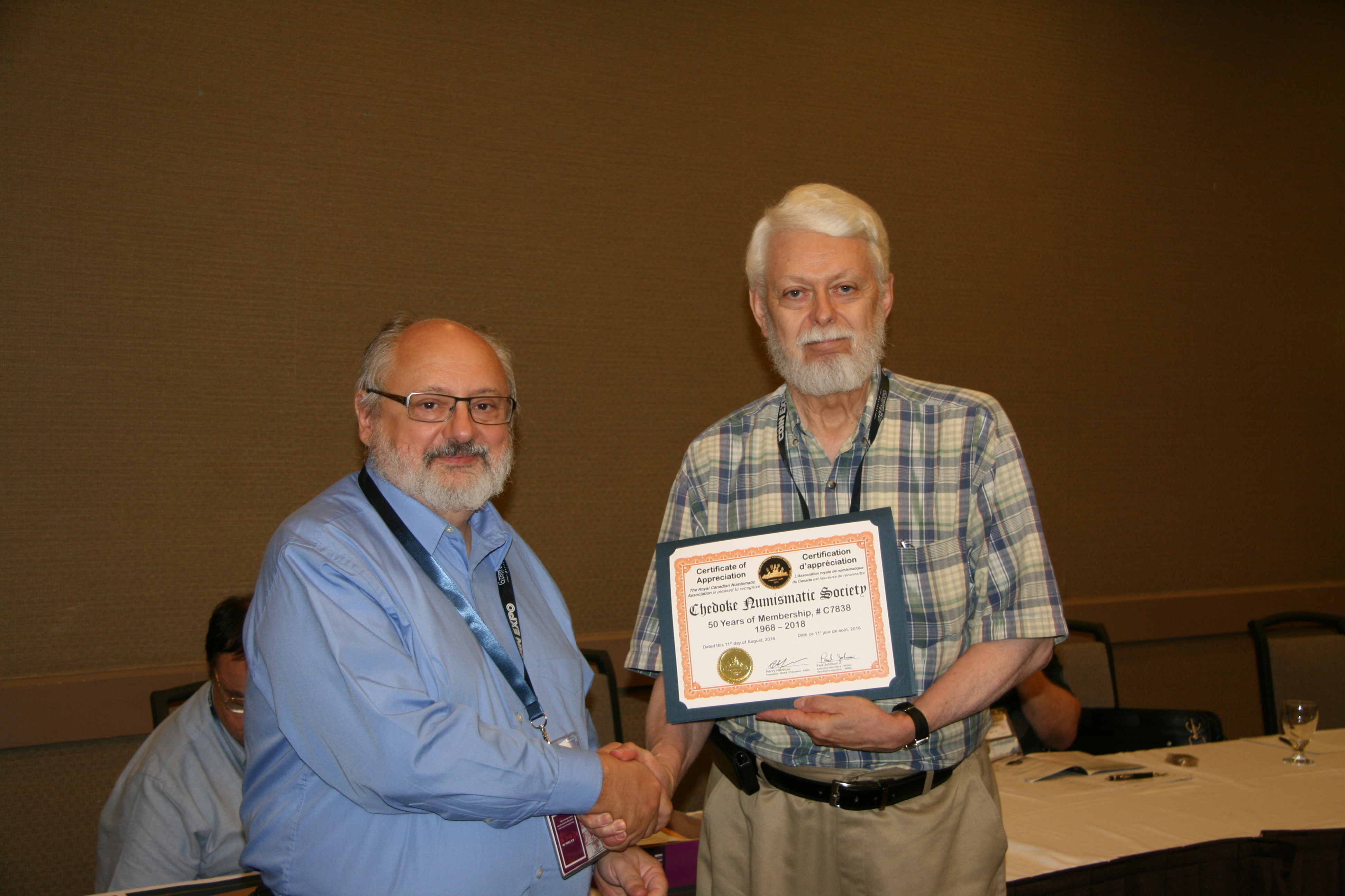 <p><strong>Paul Petch</strong> (left) receiving the 50 years of membership recognition award for the <strong>Chedoke Numismatic Society</strong> from <strong>Henry Nienhuis</strong> (right).<br /> <small>Dan Gosling photo</small></p>